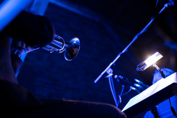 A trumpet player playing the trumpet in a big band concert on stage with blue stage lights