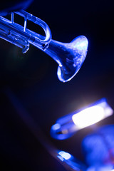 A trumpet player playing the trumpet in a big band concert on stage with blue stage lights © Janisphoto