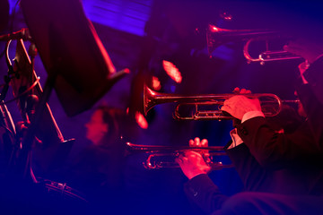 Plakat Musicians of a big band trumpet section are laying down some smooth jazz all dressed in concert black during a live show in a venue with red lights and blue lights making streaks in fron of the camera