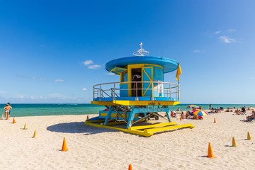 People on Miami beach on beautiful sunny day. Sand beach, tourists and yellow lifeguard tower on...