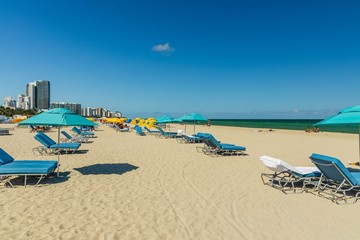 Beautiful landscape view of Miami South  Beach coast line. Sand beach, Atlantic Ocean. Blue sunbeds under sun umbrellas on turquoise water and blue sky  background.  USA. Miami Beach.