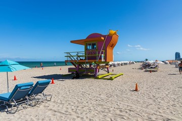 People on Miami beach on beautiful sunny day. Sand beach, tourists and yellow lifeguard tower on...