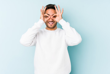 Naklejka premium Young caucasian man isolated on blue background excited keeping ok gesture on eye.