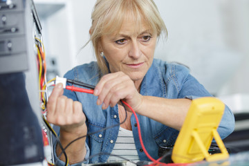 senior female technician using voltage meter