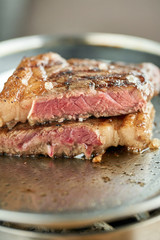 Metal Plate on red coal with Grilled striploin steak . The strip steak or New York strip. Barbecue restaurant menu. Medium rare