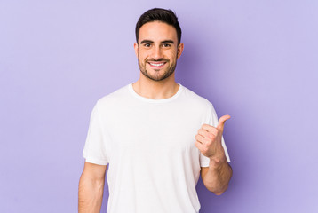 Young caucasian man isolated on purple background smiling and raising thumb up