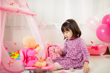 Obraz na płótnie Canvas toddler girl pretend play baby care at home against white background