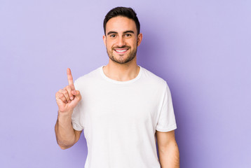Fototapeta premium Young caucasian man isolated on purple background showing number one with finger.