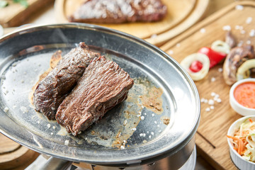 Grilled fillet steaks. A piece of meat cut in two. Barbecue restaurant menu. On a metal plate with coal. Chateaubriand Steak