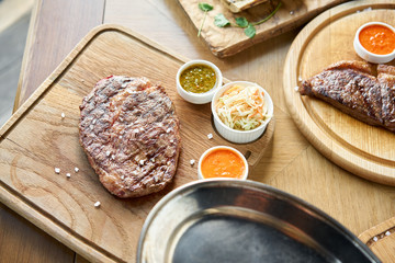 The waiter cutting Rib eye steak on wooden board. Barbecue restaurant menu.