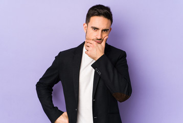 Young caucasian man isolated on purple background contemplating, planning a strategy, thinking about the way of a business.