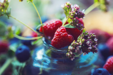 Raspberry berries and oregano flowers close-up. Beautiful fruit background for seasonal herbal tea. Aromatic ingredients. Background from berries, herbs and beautiful bokeh