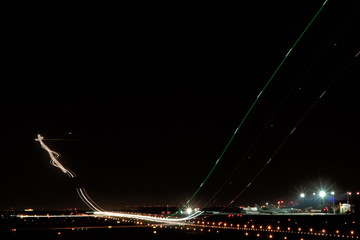 long time exposure of an aircraft taking off and landings with the back light forming a curve into...