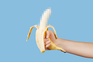 Hidden censored banana in hand on a blue background. Horny (aroused) penis, male erection and...