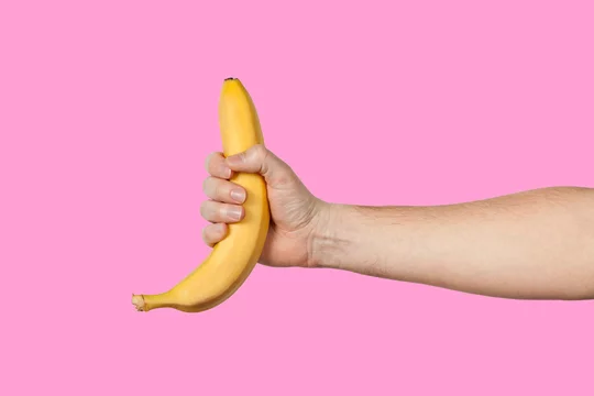 Banana as a symbol of male penis in hand on a yellow background hidden by censorship. Sexual masturbation and orgasm, impotence problem. Self-pleasure concept.