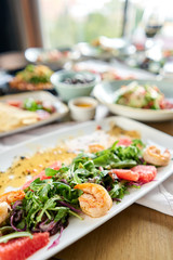 Fresh salad with grilled shrimps, slice grapefruit and arugula salad and spicy fried prawns. Restaurant menu, natural and organic food concept.