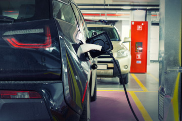Electric car at charging station indoor underground parking in basement floor office, mall or...