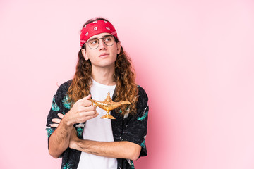 Long hair caucasian man holding a magic lamp isolated smiling confident with crossed arms.