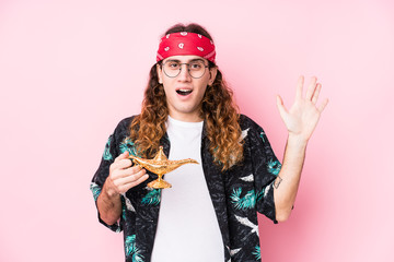 Long hair caucasian man holding a magic lamp isolated celebrating a victory or success