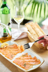 Closeup of salted and smoked salmon or trout fillet on a fork . Thin slices of red fish with lemon close up. Restaurant menu