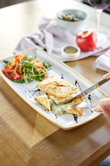 Woman eats Latin American fried empanadas with Vegetable salad with arugula. Decorated with balsamic sauce. Menu restaurant