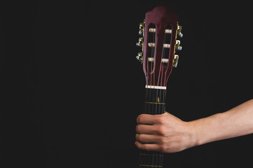 Hand holds guitar. acoustic musical instrument on black background