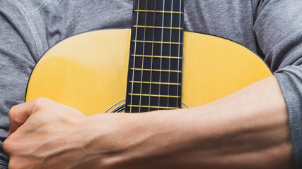 Man holds acoustic guitar. string instrument close up