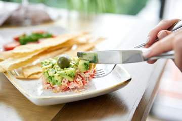 Woman eats salad crab, avocado, citrus oil, spices. Crab meat with matzo on white plate for cooked seafood.