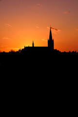 Naklejka premium Church building exterior in silhouette of sunrise or sunset with glowing sunlight