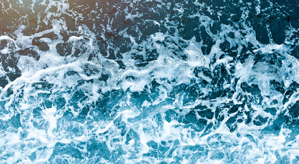 Background shot of aqua sea water waves surface. Blue ocean water and foam aerial view.