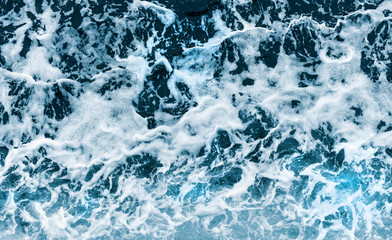 Background shot of aqua sea water waves surface. Blue ocean water and foam aerial view.