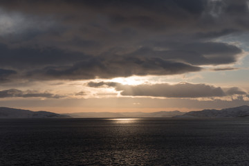Fototapeta na wymiar Wolkenformation mit durchscheinenden Sonnenstrahlen und Reflektion auf dem Wasser, Abendrot, Sonnenaufgang