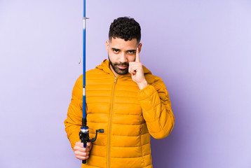 Young latin fisherman holding a rod isolated Young latin fisherman holding a Young latin man...