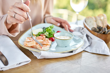 Grilled Argentine shrimp with mango-jalapeno sauce. Lunch in a restaurant, a woman eats delicious and healthy food. Delicious fresh seafood prawns with fresh vegetables and lime. Cream sauce