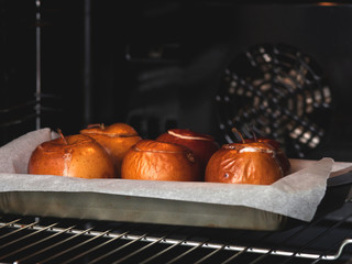 Homemade baked apples in the oven, with parchment on a baking sheet close-up.