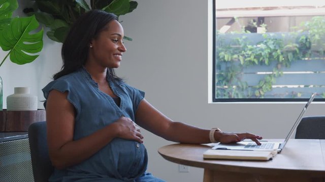 Pregnant African American Woman Using Laptop At Table Working From Home