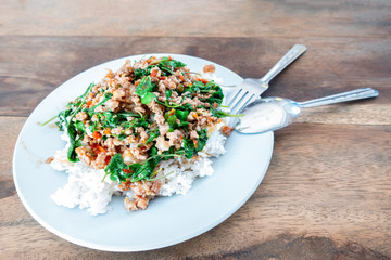 Rice topped with stir-fried pork and basil in a white dish. (Front focus)