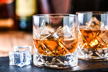 Glass of whiskey with ice cubes on black stone table. Side view with copy space alcohol concept.