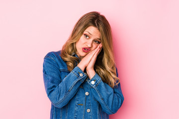 Young caucasian woman isolated on pink background yawning showing a tired gesture covering mouth with hand.