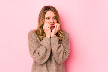 Young caucasian woman isolated on pink background biting fingernails, nervous and very anxious.