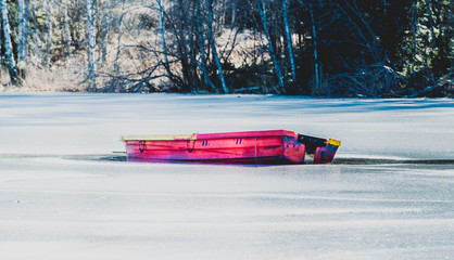 Czerwona mała łódka na lodzie pośrodku zamarzniętego jeziora