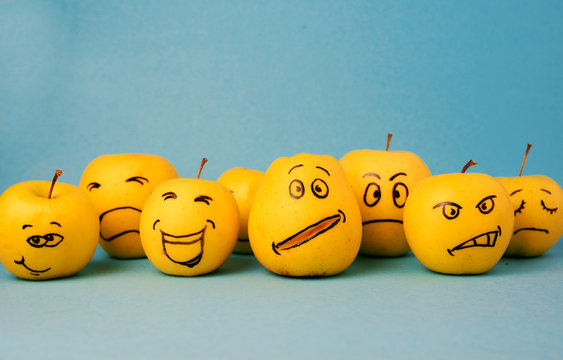 different emotions from joy to sadness and anger Face on an apple - abstract image of human emotions on blue background 