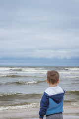 The little boy looks at the rough sea waves