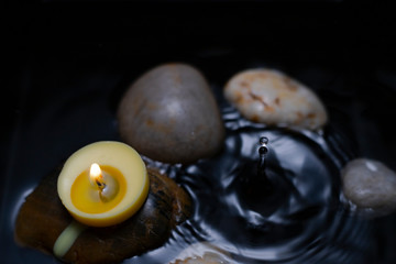 burning candle over water with rocks