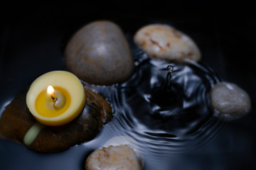 burning candle over water with rocks