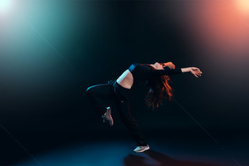 Fototapeta na wymiar brunette girl shows different dance elements on a dark background