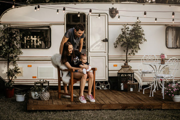 Young family near the trailer, dad, mom and daughter live in a motor home