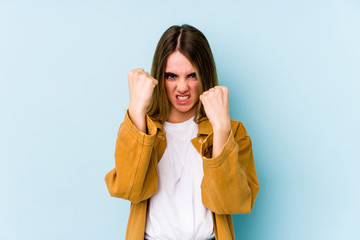 Young caucasian woman isolated on blue background upset screaming with tense hands.