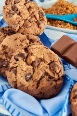 plate of cocoa cookies, brown cane sugar and chocolate, with blue tones on napkin, wooden table, tablecloth and spoon