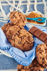 plate of cocoa cookies, brown cane sugar and chocolate, with blue tones on napkin, wooden table, tablecloth and spoon